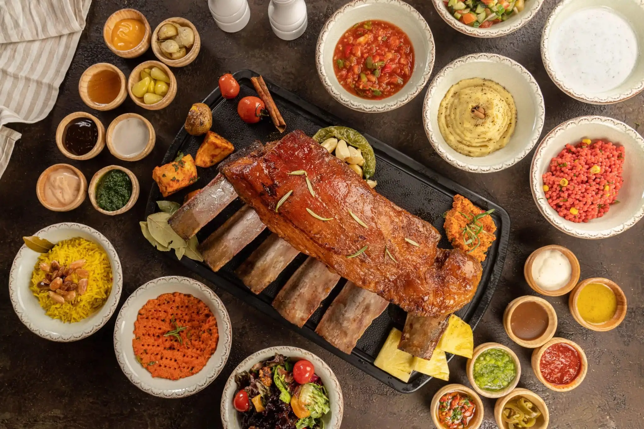 A shared spread of smoked halal beef ribs, salads and sauces for a group lunch